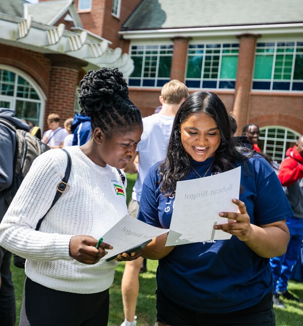 Two international students look at a sheet of paper during an Orientation game on a sunny day