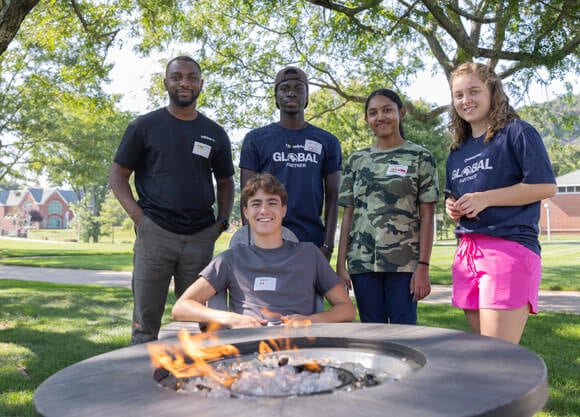 International students standing in front of a firepit during orientation