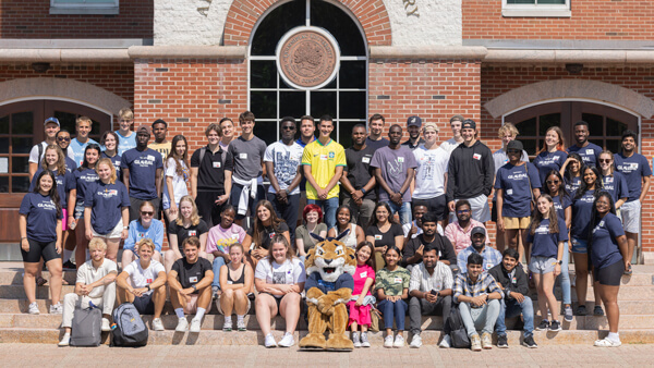 Dozens of Global Partners program members pose for a photo on the library steps with the Bobcat mascot