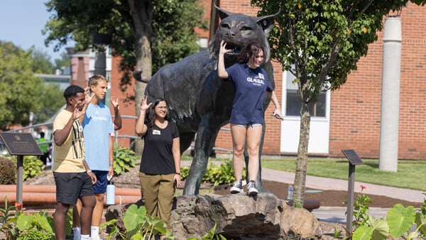 Four international students pose for a photo with the Bobcat statue